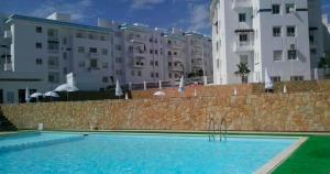 a swimming pool in front of some buildings at Résidence Bab Sebta in Fnidek