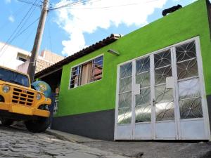 a yellow truck parked in front of a green building at Suite na Montanha Magica in São Thomé das Letras