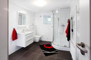 a white bathroom with a shower and a sink at Villa Z - apartment with private parking in Brno