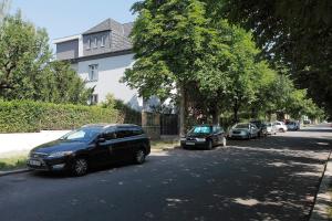 eine Reihe von Autos, die an der Straßenseite geparkt sind in der Unterkunft Villa Z - apartment with private parking in Brünn