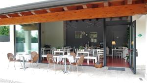 Corte Mantovani في كولا دي لاتيزي: مطعم أمامه طاولات وكراسي بيضاء