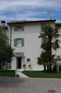 a white house with a palm tree in front of it at Corte Mantovani in Colà di Lazise