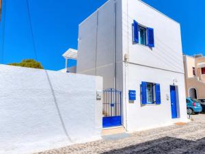 a white building with blue doors and a fence at Folia Apartments in Fira