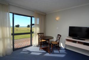 a living room with a table and chairs and a television at Harbour View Motel on Ahuriri Beach in Napier NZ with sea view suites in Napier