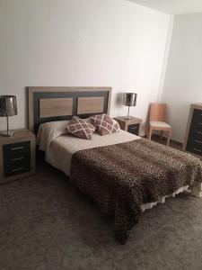 a bedroom with a bed with two tables and two lamps at Apart Juan de Cardona in Arinaga