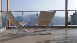 two chairs sitting on a balcony looking out at the ocean at Anna Apartments in Sarandë