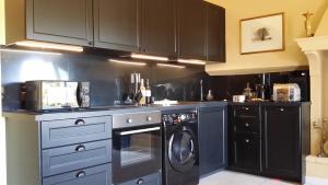 a kitchen with black cabinets and a washer and dryer at La Dame Au Balcon in Roussillon