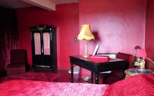 ルシヨンにあるLa Dame Au Balconの赤い壁のベッドルーム1室(デスク付)