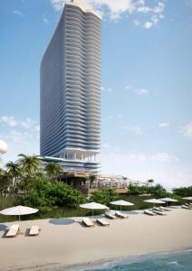 a beach with chairs and umbrellas in front of a tall building at LYFE 4111 S Ocean dr in Hollywood