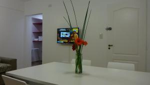 een vaas met bloemen op een tafel met een tv bij Depto calle 18 - soleado y con balcon in La Plata