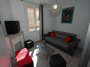 a living room with a couch and a tv at Maison Vauban Plus in Saint-Raphaël