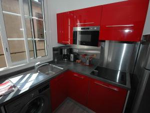 una cucina con armadi rossi e una lavatrice di Maison Vauban Plus a Saint-Raphaël