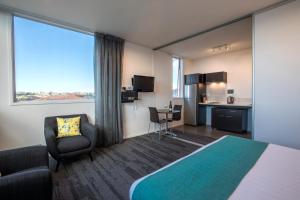 a hotel room with a large bed and a kitchen at Quest Henderson Serviced Apartments in Auckland
