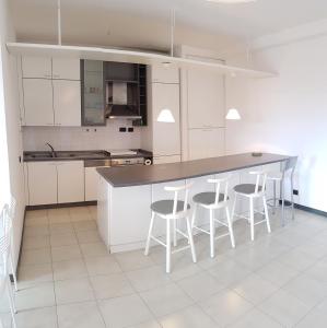 a kitchen with white cabinets and a counter with stools at Condominio Stefania in Ameglia