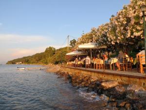 um grupo de pessoas sentadas num restaurante junto à água em Akrogiali Rooms em Boukari