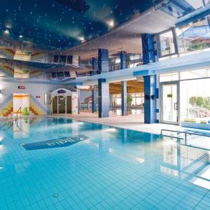 a large swimming pool in a large building at Pensjonat Tadeusz i Apartamenty w Darłówku in Darlowko