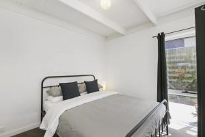 a white bedroom with a bed and a window at Mysa Anglesea Sleeps 7 WiFi SmartTV Cafes Shops in Anglesea