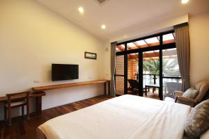 - une chambre avec un lit, une télévision et un canapé dans l'établissement 海景擁月星宿民宿, à Chenggong