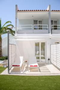 a white house with two chairs and a table at Kouros Seasight Hotel in Pythagoreio
