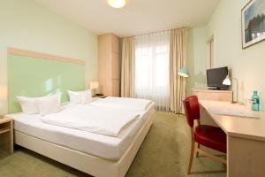 a bedroom with a white bed and a desk and a chair at BHB - Boutique Hotel Buchholz in Buchholz in der Nordheide +21 photos