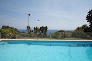a large blue swimming pool with the ocean in the background at Monaco Country Park in Roquebrune-Cap-Martin