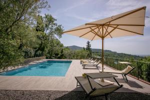 a swimming pool with chairs and an umbrella at Casolare Il Condottiero Holiday House in Castiglion Fiorentino