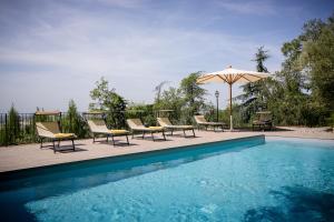 un grupo de sillas y una sombrilla junto a la piscina en Casolare Il Condottiero Holiday House, en Castiglion Fiorentino