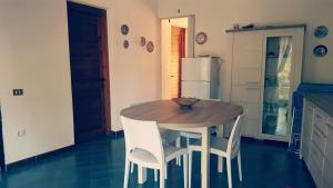 サンタ・マルゲリータ・ディ・プーラにあるPinus Village - Da Nonna Luisaのキッチン(木製テーブル、白い椅子付)