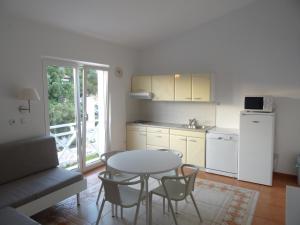a kitchen with a table and some chairs and a table and a kitchen with at Neva Apartments in Šimuni