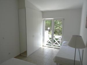 a white room with a bed and a sliding glass door at Neva Apartments in Šimuni