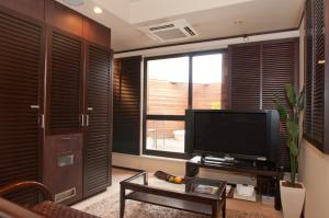 a living room with a television and a large window at Hotel Rplus in Yachiyo