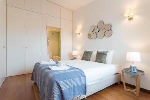 een slaapkamer met een wit bed en een blauwe deken bij Alfama Modern Two-Bedroom Apartment w/ River View and Parking - by LU Holidays in Lissabon