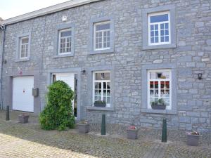 een stenen gebouw met witte ramen en een struik bij Stylish Holiday Home in Han sur Lesse with Terrace in Han-sur-Lesse