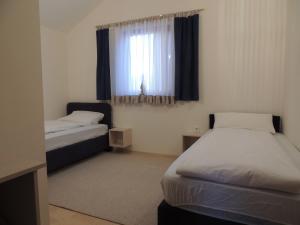 Una pequeña habitación con dos camas y una ventana. en Apartments Villa Aurora, en Ražanac