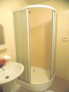 a shower with a glass door next to a sink at Elektromash Hotel in Tiraspol