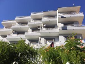 Un edificio alto y blanco con árboles delante. en Hotel Sacratif, en Torrenueva