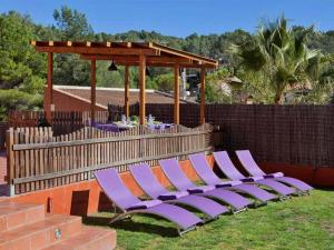 una fila de tumbonas púrpuras en un patio trasero en Villa Olivo Cerra da, en Canyelles