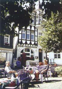 Un groupe de personnes assises autour d'une table devant un bâtiment dans l'établissement Hotel Alberga, à Mettmann