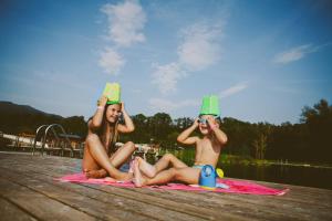 two women sitting on a dock with buckets on their heads at Hotel & Hostel Marenberg Radlje in Radlje ob Dravi