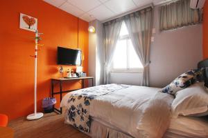 a bedroom with orange walls and a bed and a window at Light Shadow in Budai