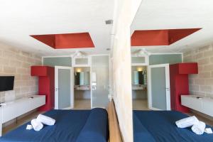 a bedroom with two beds and red and white cabinets at Cave Bianche Hotel in Favignana