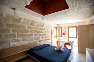 a bedroom with a blue bed and a brick wall at Cave Bianche Hotel in Favignana