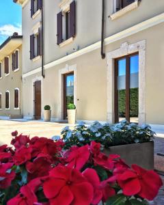 uma cama de flores vermelhas em frente a um edifício em Garda Relais em Castelnuovo del Garda