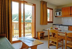 a kitchen with a table and a kitchen with a balcony at ANCOLIE 23 Les Chalets de Super D in Le Dévoluy