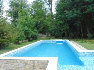 a swimming pool in a yard with a stone wall at Holiday Park Ranchoto in Kirkovo