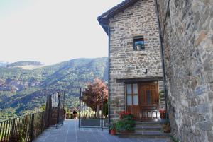 a stone building with a door and mountains in the background at Casa el Parque Cajal in Torla