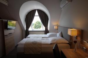 Schlafzimmer mit einem großen Bett und einem Bogenfenster in der Unterkunft Hotel Bauschheimer Hof in Rüsselsheim