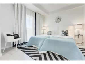 a white bedroom with a large bed and a chair at Hotel Cristal Marinha in Marinha Grande