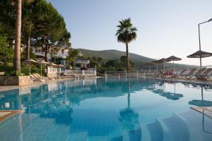 una gran piscina azul con palmeras y montañas en Greenport Bodrum Hotel, en Guvercinlik