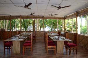 a dining room with tables and chairs and windows at Coconhuts Beach Resort in Neil Island